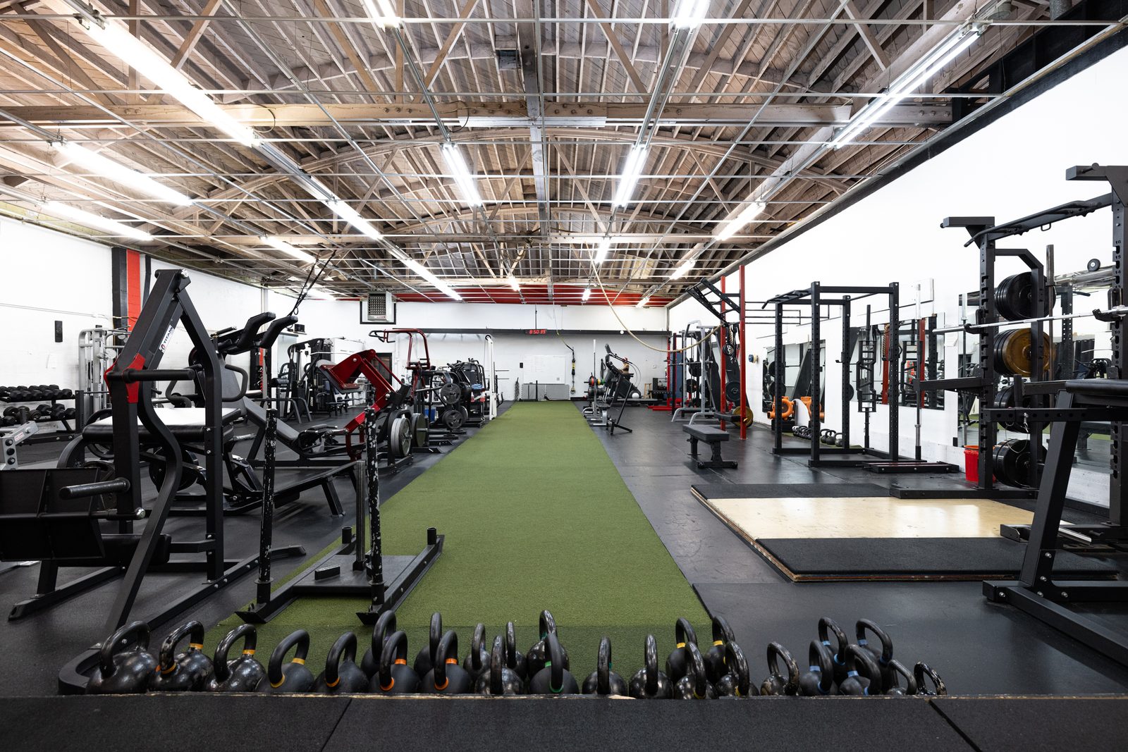 Open training floor with turf lane and kettlebell row